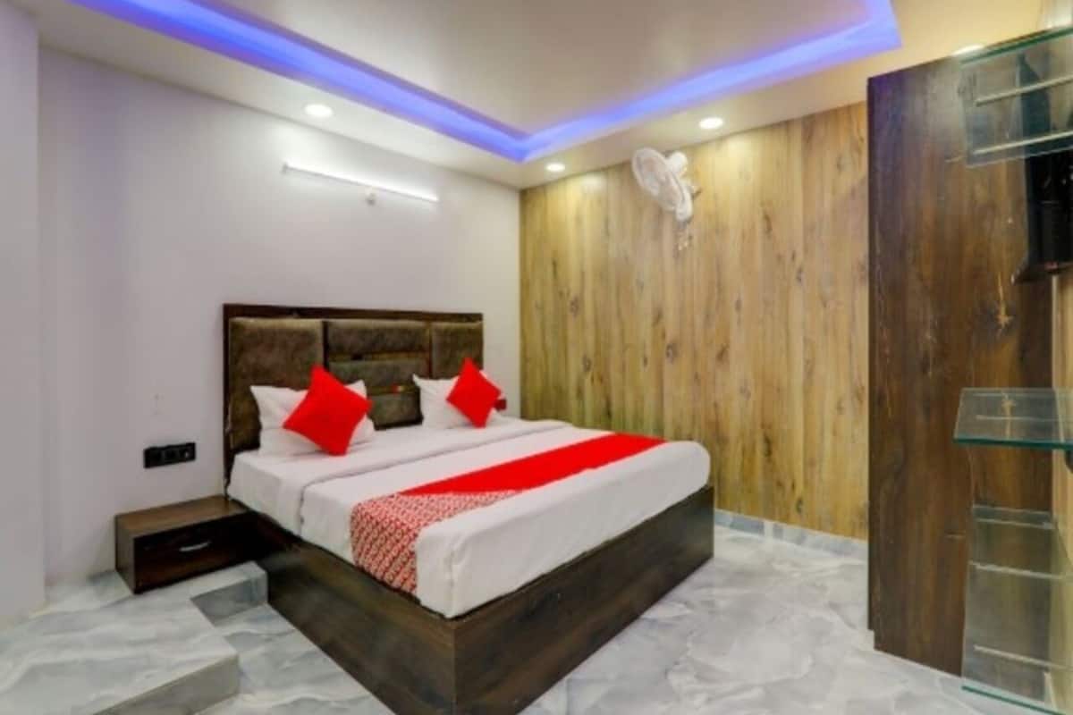 A modern bedroom with a wooden headboard, a bed with red pillows, and a glass cabinet.