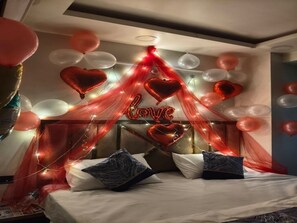 A bedroom with a bed, pillows, and a canopy with heart-shaped balloons and lights. - Hotel Luv Inn (Lucknow)