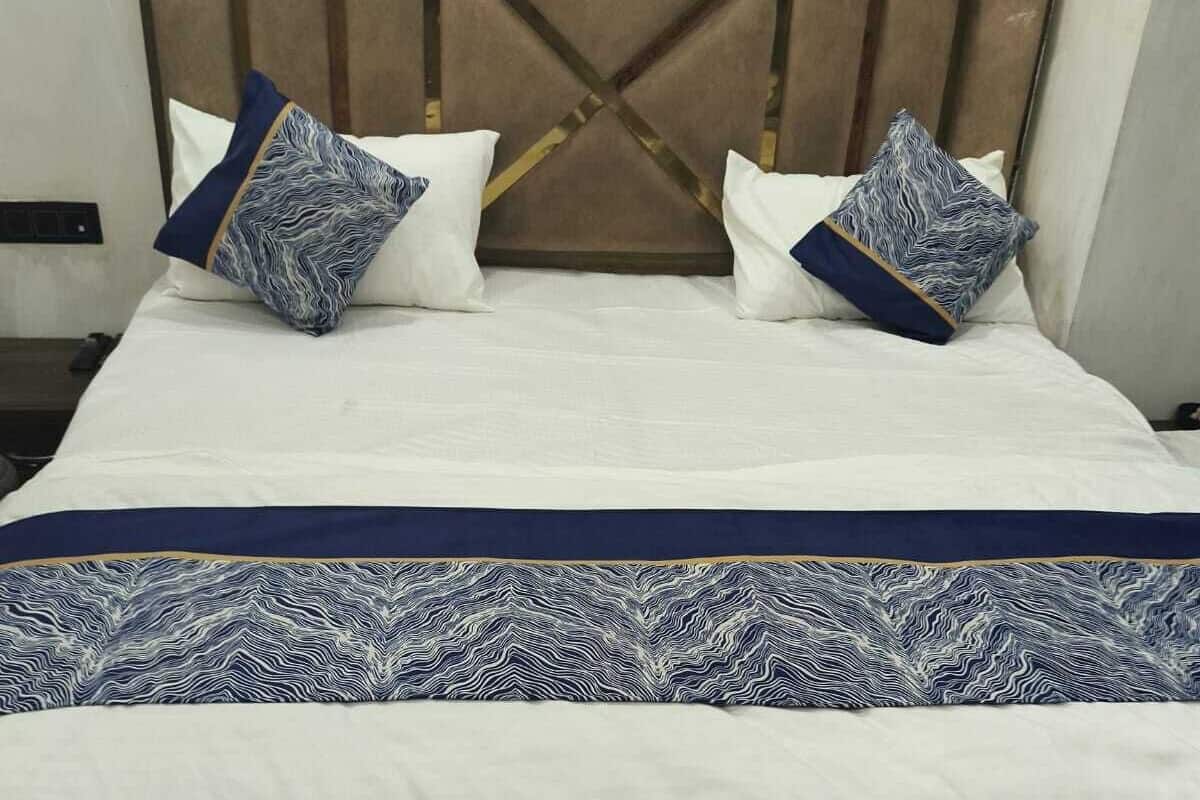 A neatly made bed with a patterned bedspread and two decorative pillows.