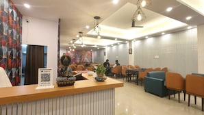 Un espace d’accueil agrémenté d’une statue de Bouddha, d’un code QR pour Google Pay et d’un coin salon avec des tables et des chaises.