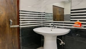 Une salle de bain avec un lavabo blanc, des carreaux noirs et blancs et une porte en bois.