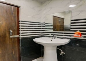 A bathroom with a white sink, black and white striped tiles, and a wooden door. - Hotel Luv Inn (Lucknow)