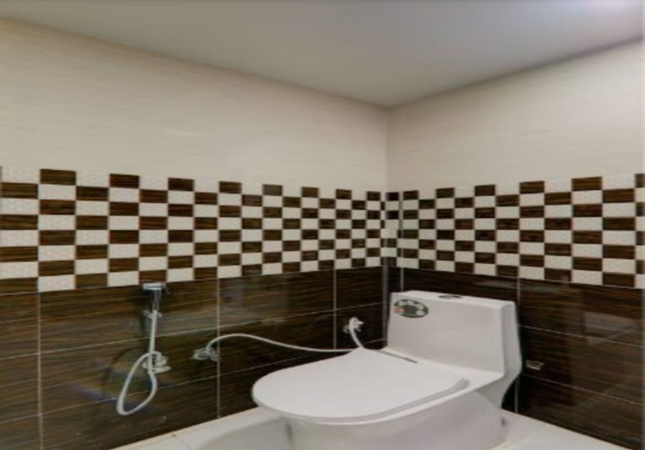 Een badkamer met een wit toilet, een douche en een betegelde muur met een ruitpatroon.