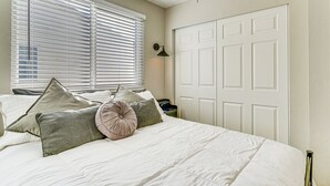 A bedroom with a bed, pillows, a nightstand, a lamp, and a door. - Stunning SLC Basecamp: Ski, Explore & Unwind (Salt Lake City)