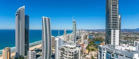 A coastal cityscape with high-rise buildings, including a distinctive curved skyscraper, and a beach in the background.