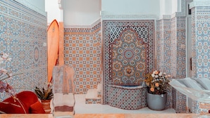 Una habitación con intrincados diseños de azulejos, una planta en maceta y una silla roja.
