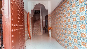 Un pasillo con pared de diseño, una escalera y una puerta con detalles decorativos.