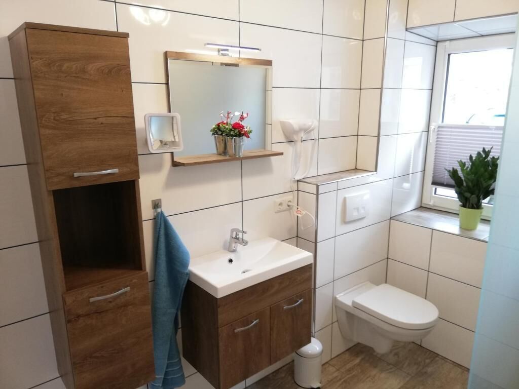 A modern bathroom with a wooden vanity, a white sink, and a toilet.
