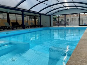 Ein Innenpool mit klarem Wasser, Fliesenboden und Glasdach.