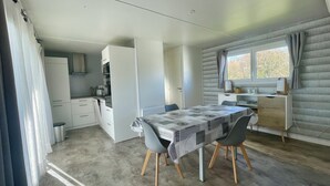 Een compacte keuken met moderne apparaten, een eethoek met tafel en stoelen, en een raam met gordijnen.