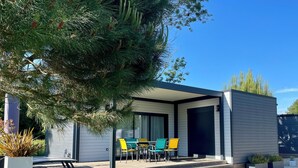 Een modern huis met een overdekt terras, tuinmeubilair buiten en een verzorgd gazon.