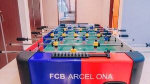 A foosball table with the FC Barcelona logo, located in a hotel room with a window and a door in the background. - Kota Bharu Family Bungalow Homestay (Kota Bharu)