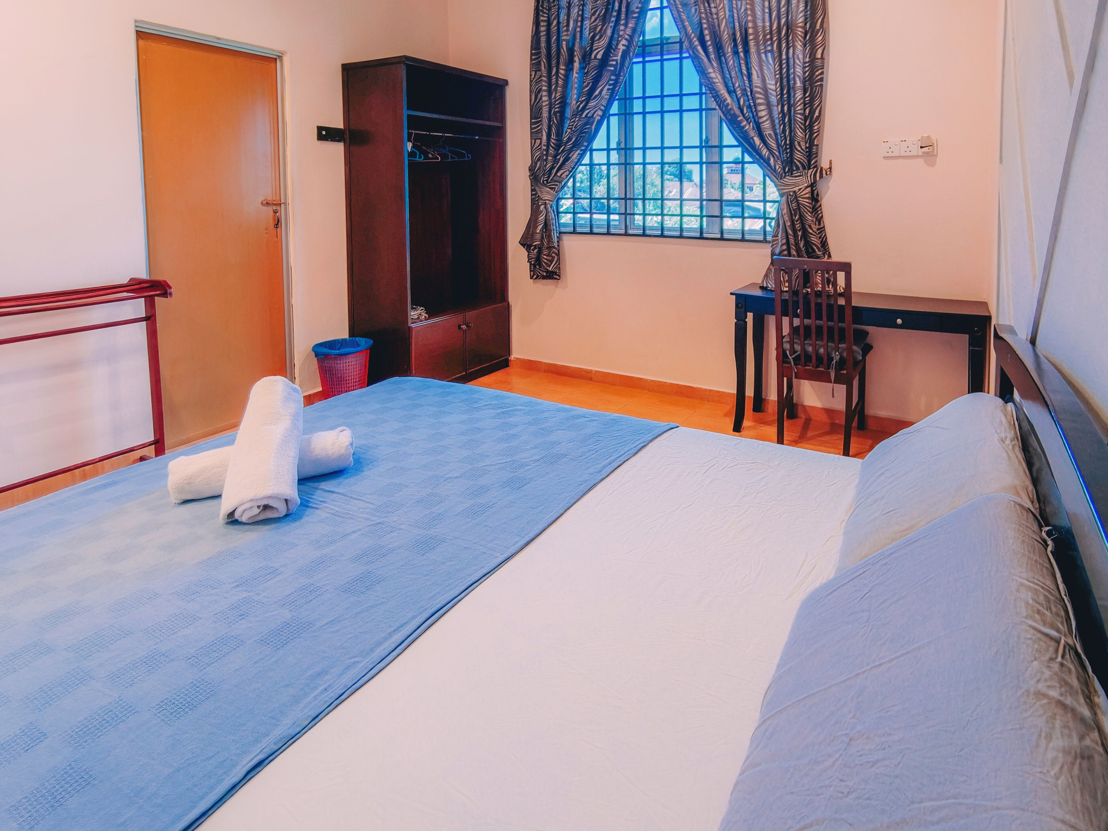 Une chambre à coucher avec un lit, une chaise, une armoire et une fenêtre avec des rideaux.