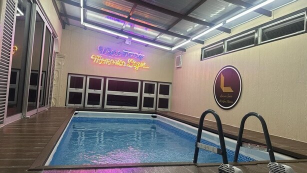 An indoor swimming pool with a neon sign reading "Welcome Family Members Begin Here" and a logo on the wall. - Kota Bharu Family Bungalow Homestay (Kota Bharu)
