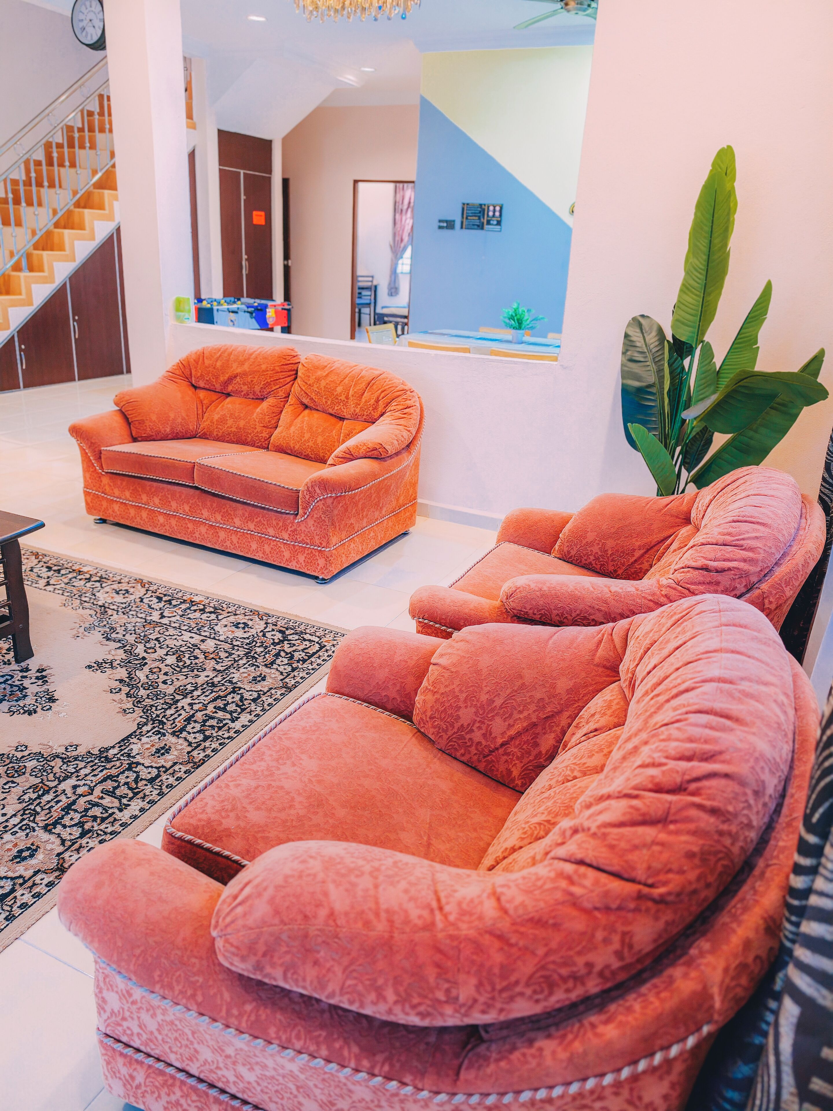 A modern living room with a sofa, a rug, and a staircase.