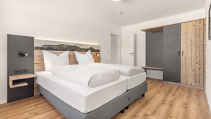 Ein modernes Schlafzimmer mit einem Bett, Nachttischen, einem Kleiderschrank und einem Bild an der Wand.