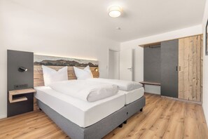 A modern bedroom with a bed, bedside tables, a wardrobe, and a painting on the wall. - Vacation apartment Gams 47 sqm for 5 persons (Samerberg)