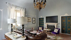 Un salon avec un lustre, une cheminée, un téléviseur et un canapé en cuir.