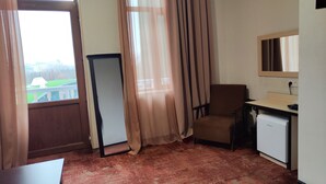 Quarto com escrivaninha, cadeira e um pequeno frigorífico.