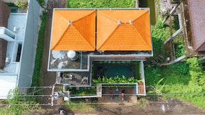 Vue aérienne d’une maison à deux étages, dotée d’une piscine et d’un espace clos où se trouvent des vélos.