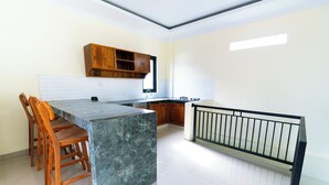 Une cuisine dotée d’un îlot en marbre, de chaises en bois, d’un meuble en bois et d’une rambarde noire.