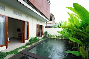A modern house with a swimming pool, sliding glass doors, and lush greenery. - Toograss Villa Ubud (Ubud)
