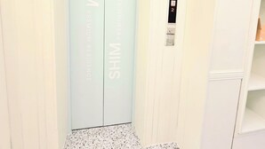 A hotel elevator with a light blue interior and the words "SHIM PREMIUM RESIDENCE" on the doors. - Shim Stay (Anyang)