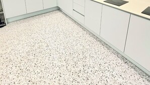 A modern kitchen with white cabinets, a granite countertop, and a speckled floor. - Shim Stay (Anyang)