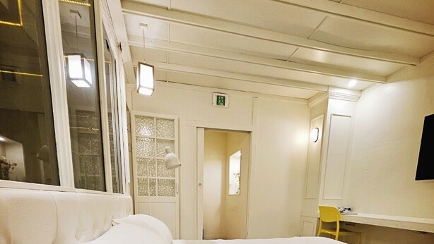 A hotel room with a large bed, a bedside table with a lamp, a chair, and a TV mounted on the wall. - Shim Stay (Anyang)