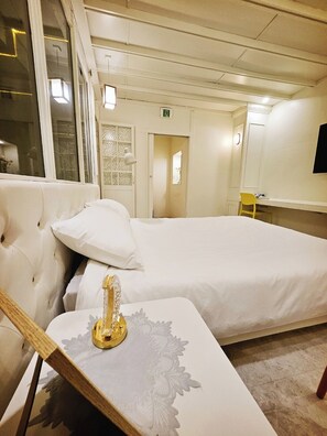Une chambre d’hôtel avec un grand lit, une table de chevet avec une lampe, une chaise et un téléviseur fixé au mur.