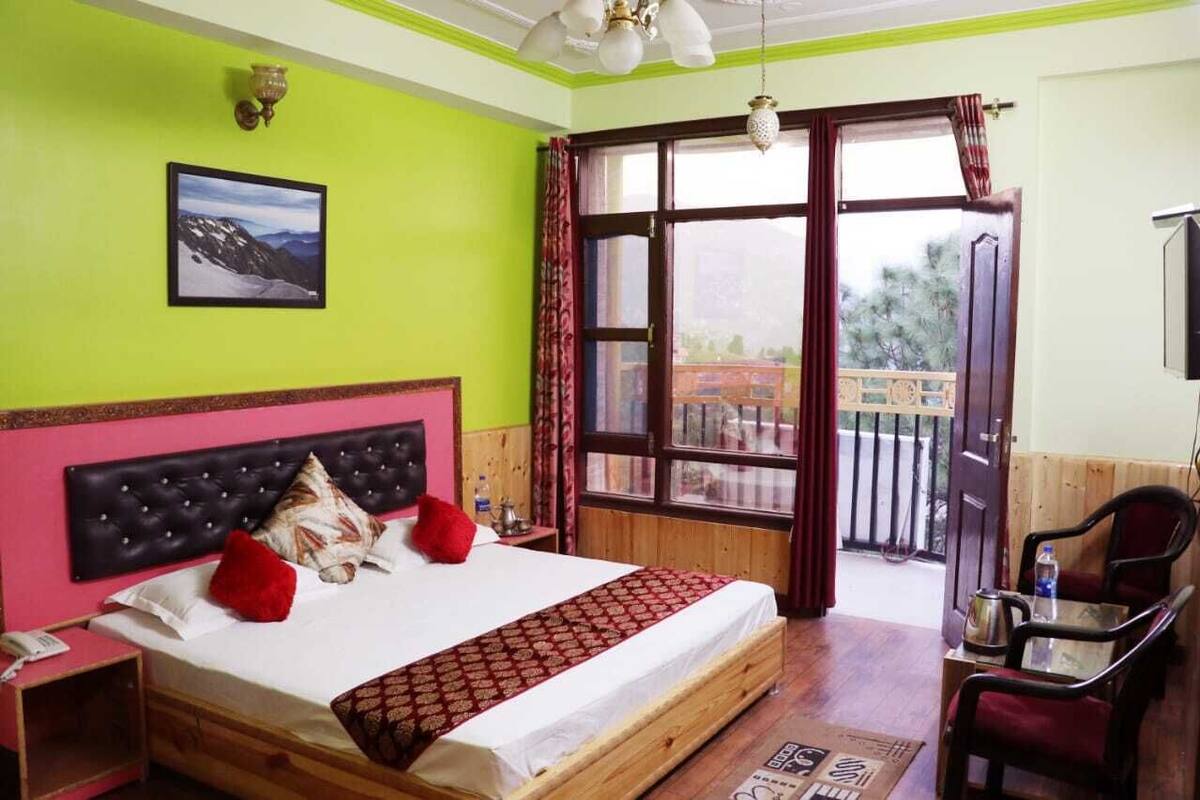 A room with a bed, a chair, a table, a window, and a picture on the wall.