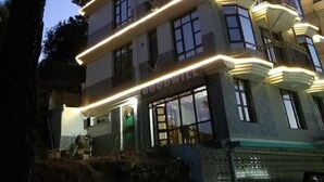 Un hôtel à plusieurs étages, doté d’une architecture moderne, de balcons et d’un éclairage extérieur décoratif.