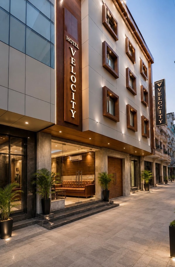 A hotel with a modern facade, large windows, and a prominent entrance with a seating area.