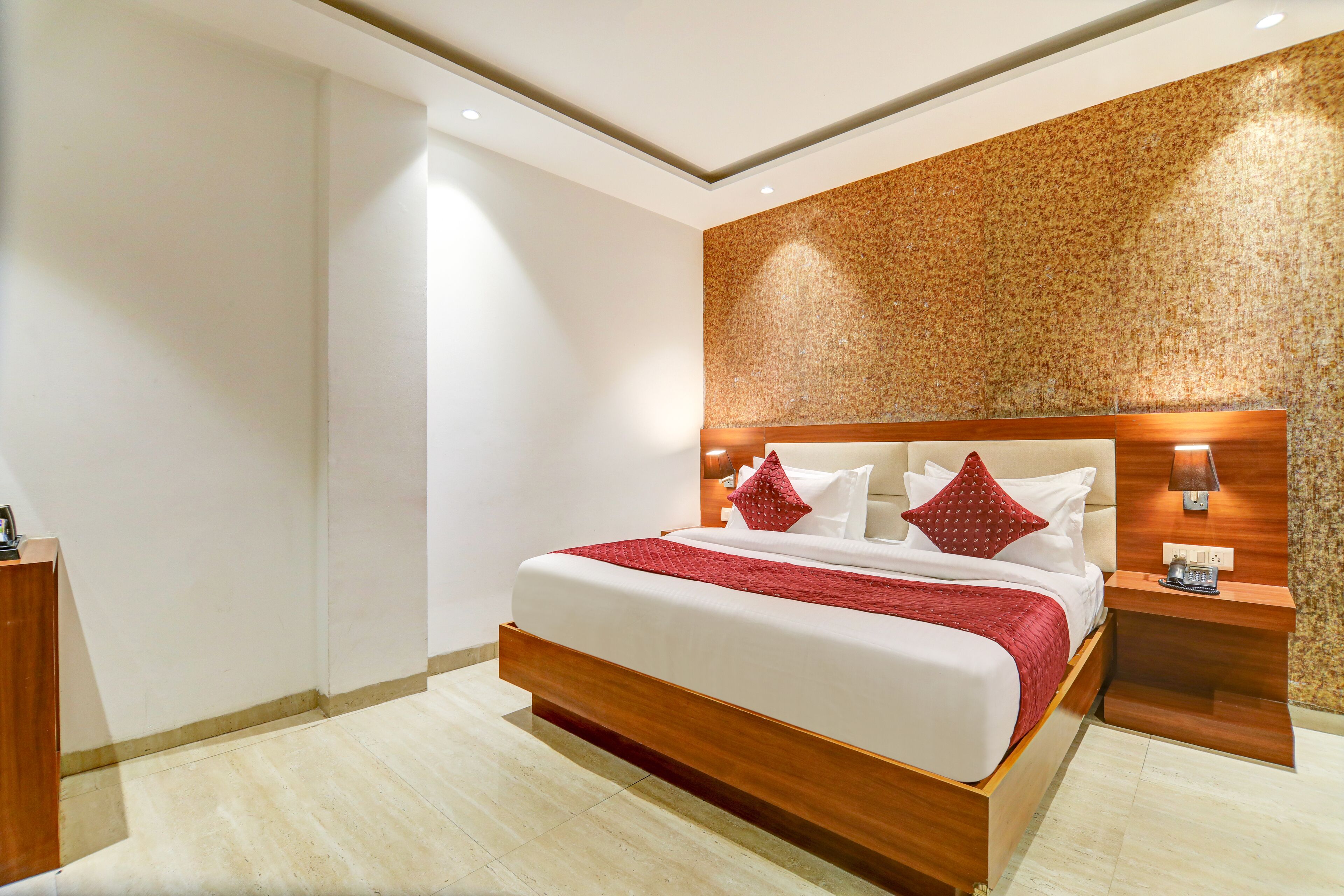 A modern hotel room with a large bed, wooden headboard, and a textured wall.
