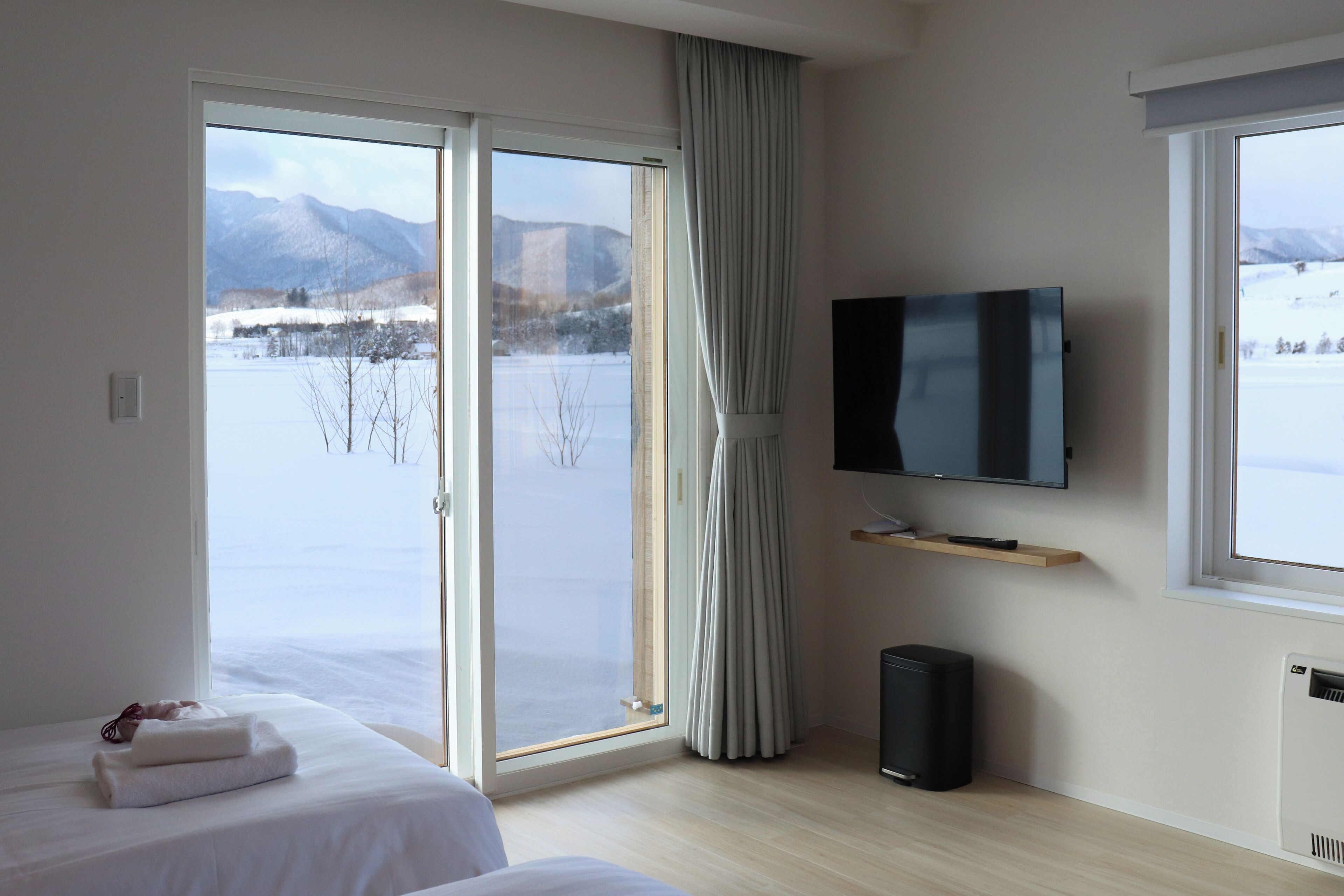 Een hotelkamer met een groot raam, een flatscreen televisie, een verwarming en een bed met een opgevouwen handdoek.