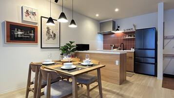 A modern kitchen with a wooden dining table, chairs, and pendant lights.