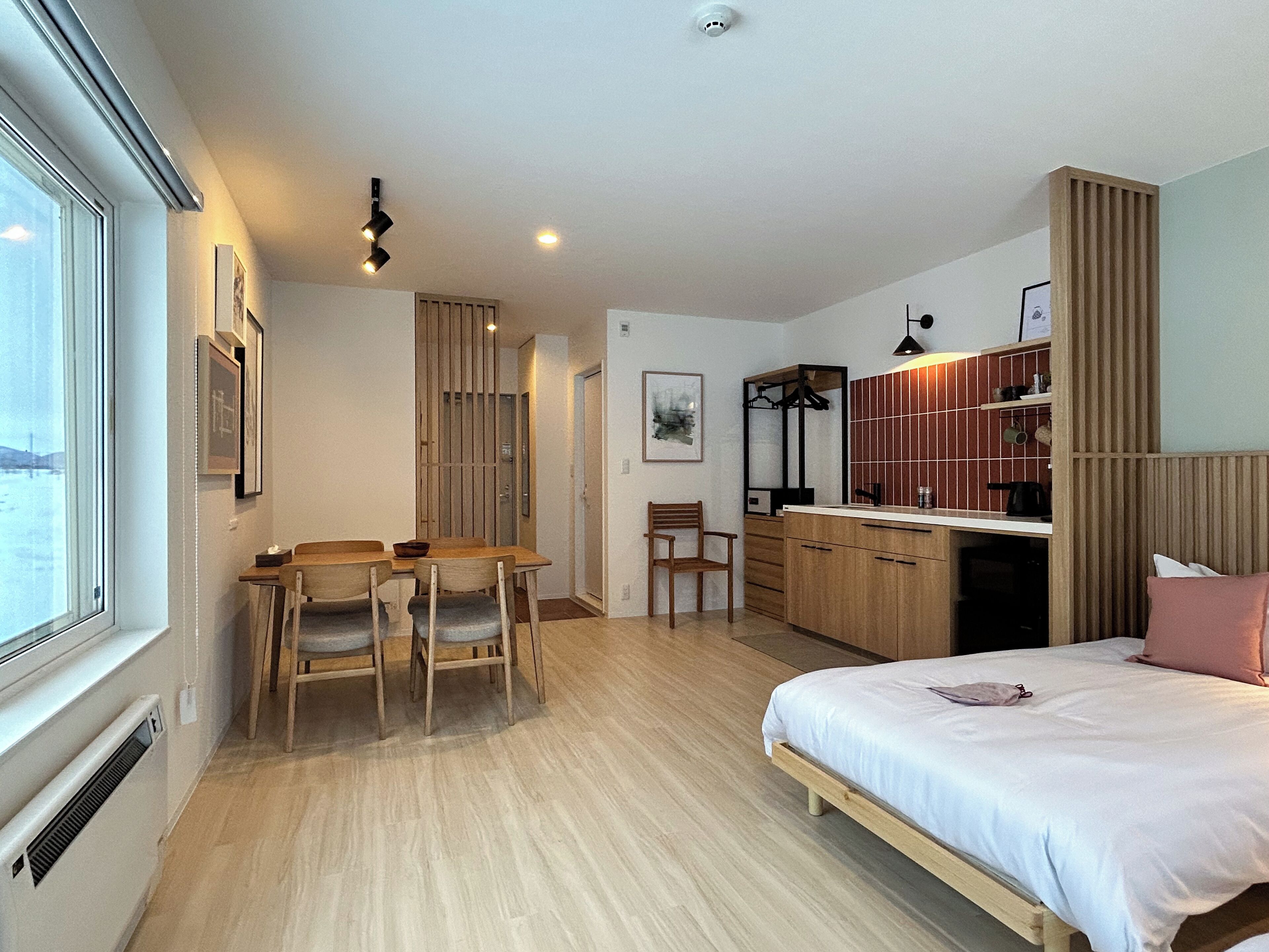 Une chambre moderne avec un grand lit, un bureau en bois et un coin repas.