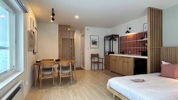 Une chambre moderne avec un grand lit, un bureau en bois et un coin repas.