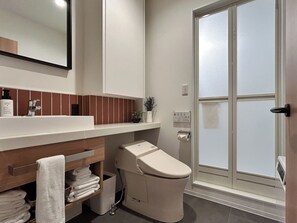 Une salle de bain moderne avec un lavabo blanc, des toilettes et une porte de douche en verre.