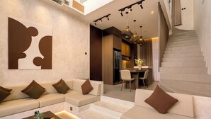 A modern living room with a sofa set, a coffee table with fruit, a staircase, and a dining area. - Villa Fresko 3 by Alfred in Bali (Munggu)