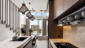 A modern kitchen with a curved countertop, a built-in stove, pendant lighting, and a view to the outdoor area. - Villa Fresko 3 by Alfred in Bali (Munggu)
