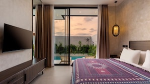 A modern hotel room with a large bed, a flat-screen TV, a balcony with a pool view, and a nightstand. - Villa Fresko 3 by Alfred in Bali (Munggu)
