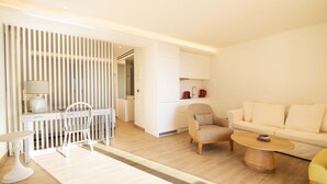 Una sala de estar moderna con un sofá, sillones, una mesa de centro y un comedor con mesa y sillas.