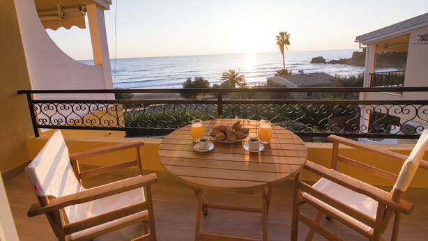 Un balcón con mesa dispuesta para el desayuno, con vista al océano.