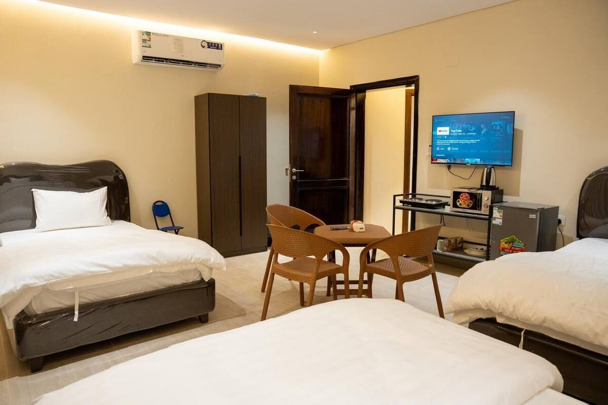 A hotel room with two beds, a desk with a chair, a TV, and a minibar.
