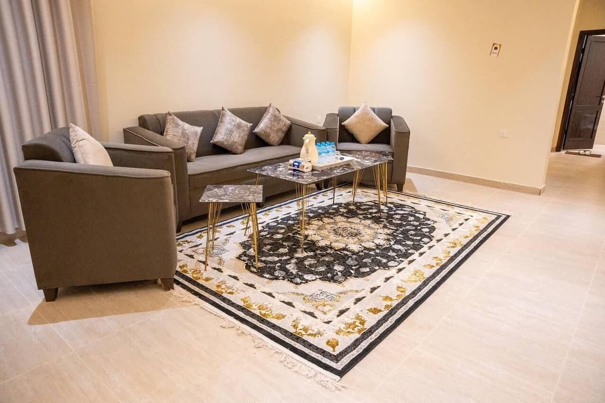 A living room with a sofa, two armchairs, a coffee table, and a patterned rug.