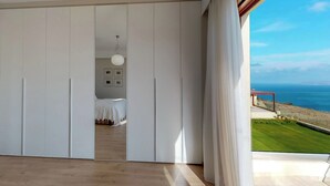 Una habitación con un amplio ventanal corredera que da a un balcón con vistas al mar.