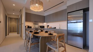 A modern kitchen with a central island, stainless steel appliances, and a chandelier. - Top floor Grande 2BR Luxe Panoramic Sea View Bohemian Style (Dubai)