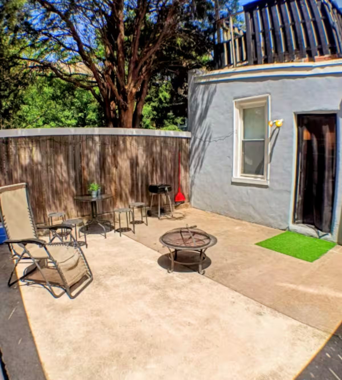 A patio area with outdoor furniture, a small table with a plant, and a window.