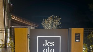 Une entrée fermée par un portail, sur laquelle est apposée une enseigne indiquant : « Jesolo Luxury Suites ».